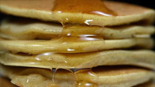 Honey flowing down a stack of pancakes, perfect for breakfast along with some coffee or milk.