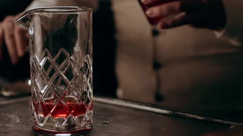 Classic bartender expertly pours red liquor shots in classy bar with soft lighting