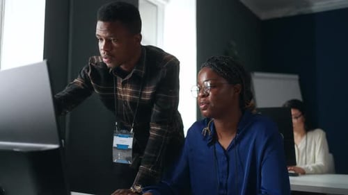 Büroangestellte diskutieren über das Projekt Afroamerikanische Männer und Frauen kommunizieren in der Nähe eines Computers