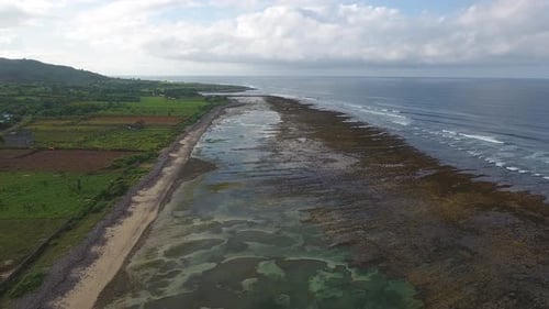 sobre el paisaje aéreo costero con llanuras de arrecifes y horizonte marino en la Indonesia tropical