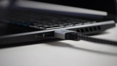 Extreme Closeup of Unrecognizable Man Unplugging HDMI Cable From Port on Side of Laptop Computer at