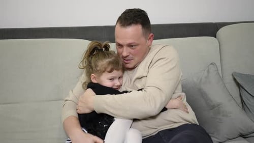 Happy Father Hugging Cute Daughter on Sofa
