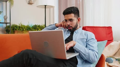 Young Adult Using Laptop on Couch at Home