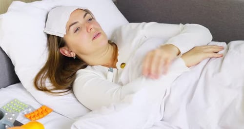Sick Woman Lying in Bed with Cold Compress