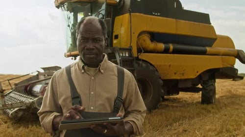 Farmer Using Tablet at Harvest with Combine