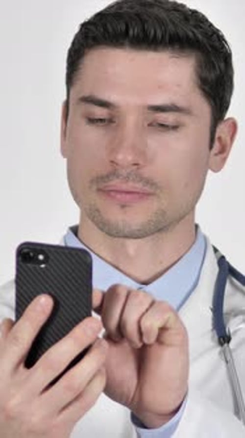 Male Doctor Using Smart Phone in White Setting