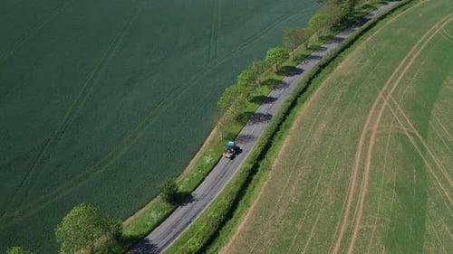 Aerial shot of a small blue tractor driving down the road