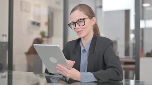 Smiling Young Woman Uses Tablet in Office