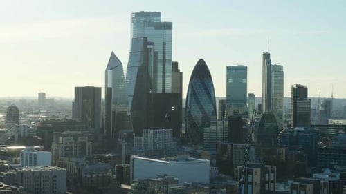 Cinematic hovering aerial shot of London financial district skyline on a warm summer morning.