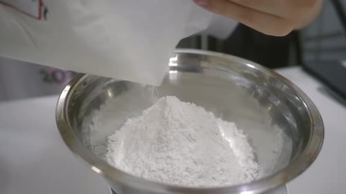 Woman Pouring White Powder Into a Silver Bowl