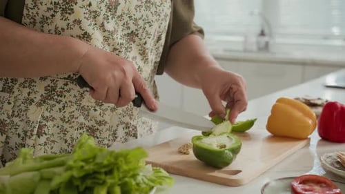 Woman Cuts Green Pepper in Sunny Kitchen