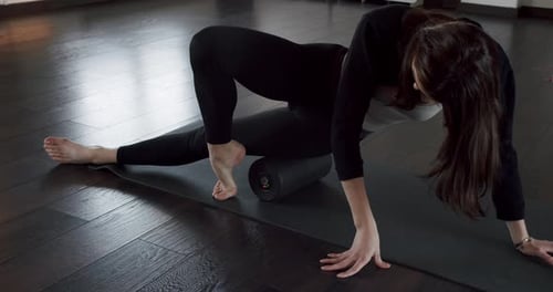 Woman Using Foam Roller on Yoga Mat