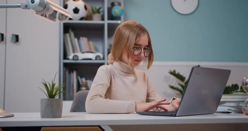 Smart Little Girl Sitting the Desk Does Homework in Her Room. Schoolgirl is Sitting at Her Desk