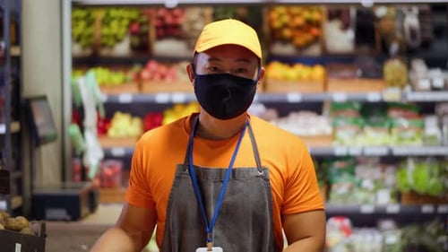 Indoor Portrait of Chinese Man Worker in Medical Black Mask Working in Grocery Store During