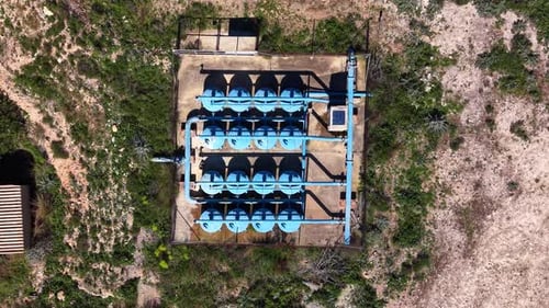 Overhead view of a water filtration station with rows of blue cylindrical tanks connected by