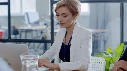 A Woman Collaborates with a Group Using Her Laptop in a Meeting