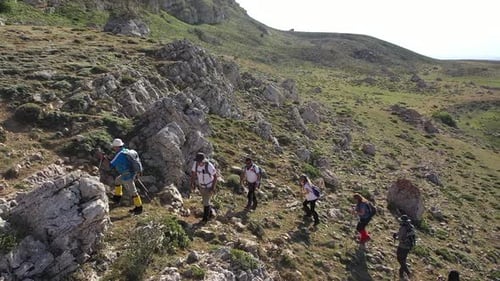Aerial View Of A Group Of People Climbing The Mountain From The Edge Of The Lake