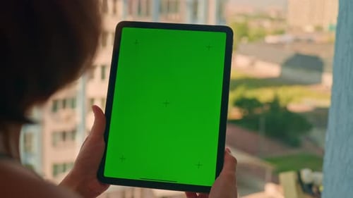 Woman Tapping Tablet with Green Screen near Building