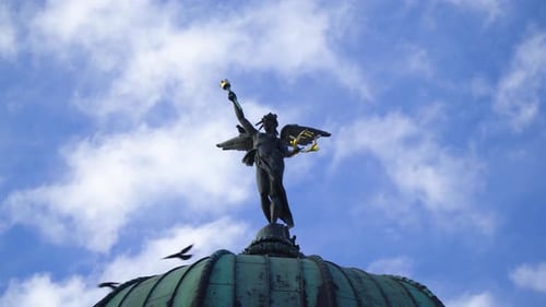 majestic state of angel woman with raised arm victorious pose golden plated clouds background mid cl