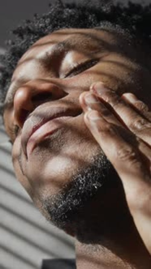 Man Applying Serum to Face in Sunlight