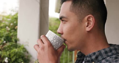 Young Adult Drinking Coffee on Porch