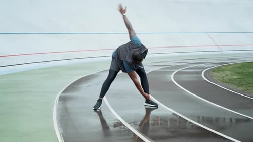 Man Stretching on a Racetrack on an Overcast Day