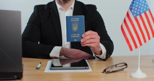 Man Holds Up Ukrainian Passport Near American Flag