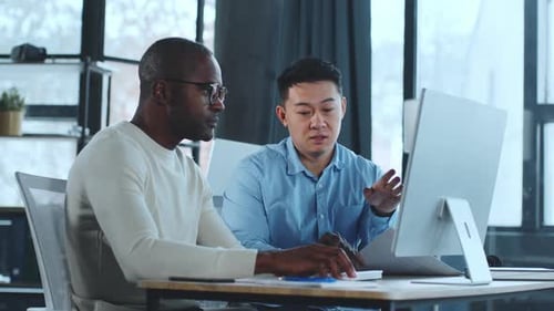 Colleagues Working Together on Computer in Modern Office