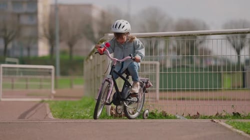 Cute Light Hair Little Girl in Helmet Learning to Ride a Real Bike on the Street but She's Not Good