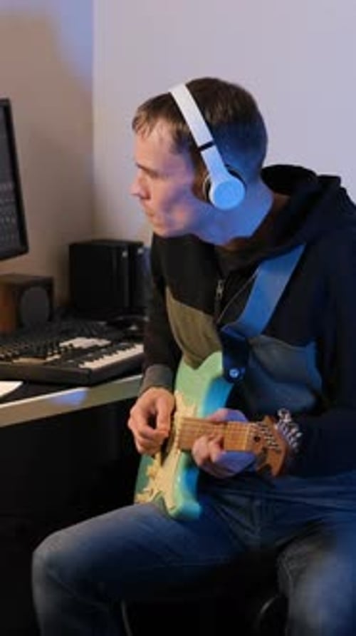Young Man Plays Electric Guitar with Headphones