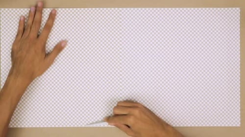 Hand smoothing a piece of checkered paper on a crafting table