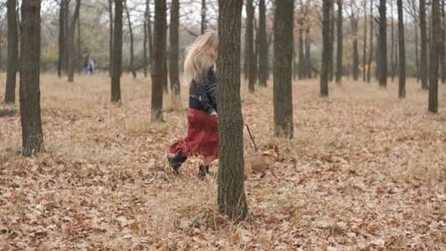 Young Beautiful Woman Runs with Her Dog in the Forest or Park