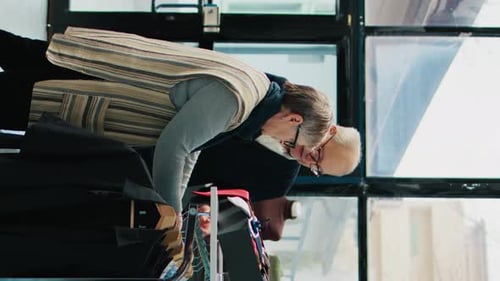 Vertical Video Elderly Customers Analyzing Elegant Shirts on Hangers at Retail Store