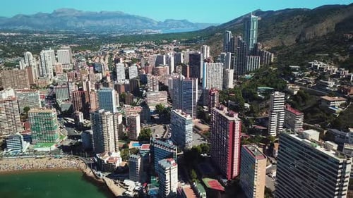 Aerial view of residential buildings near coast surrounded by beach and ocean water with mountains o
