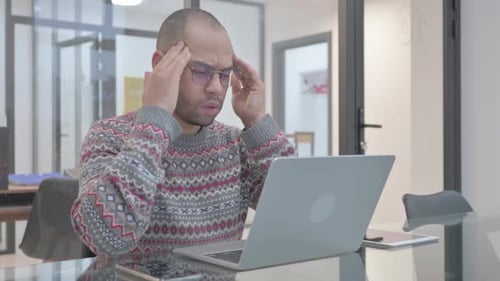 Man Using Laptop Experiencing a Headache in Office