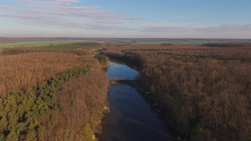 A scenic aerial view of a winding river flowing through a dense forest and open countryside.