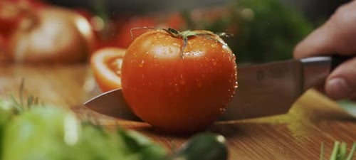 Male chef cutting a tomato