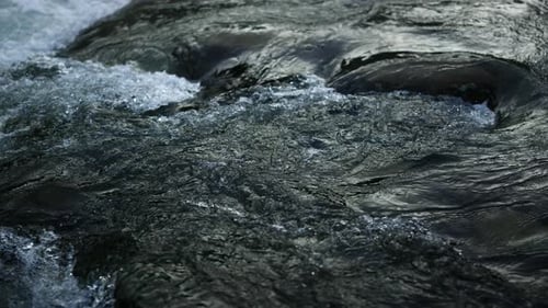 Closeup of Mountain River Surface. Abundant Water Stream Flowing Through Stone Rapids