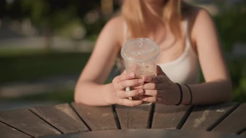 Relaxed Woman with Beverage Outdoors Young Lady Relaxes in Park Holding Iced Drink Woman Sitting at