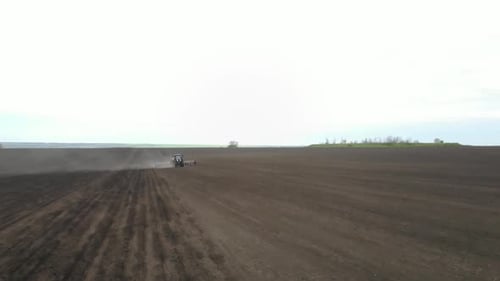 Blue tractor planting sunflower with yellow planter on the field in Ukraine