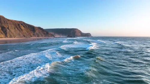 Cliff-lined beach with rolling surf waves