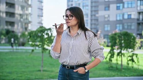 Mature Woman Recording Audio Message on Smartphone Outdoors Street Urban Style