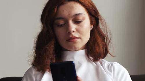 Auburn Haired Woman Using Mobile Phone Device Indoors