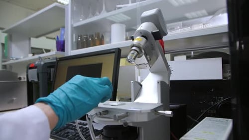 Gloved Hand Adjusting Microscope in Modern Laboratory