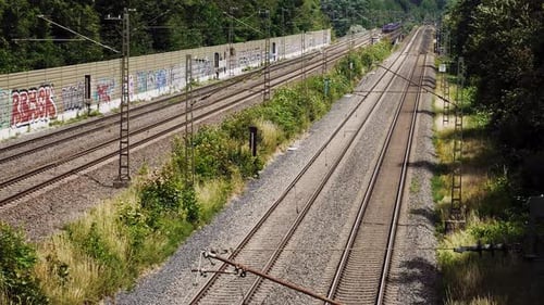Ein Zug fährt unter der Kamera vorbei, während er an einem hellen, windigen Tag in die Ferne fährt.