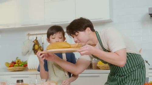 Man and Boy Smelling Bread in Kitchen
