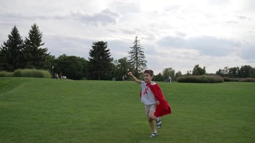 Boy in a Red Cape Running Through Meadow