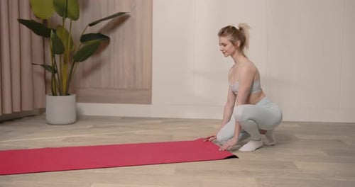 Woman Rolling an Exercise Mat on the Floor in a Yoga Studio