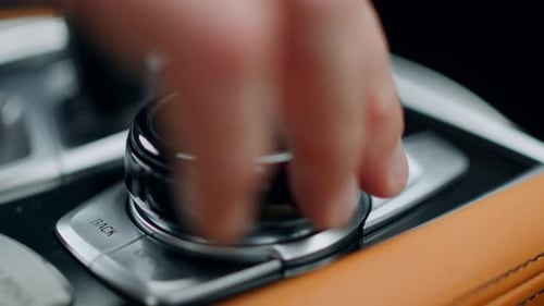 Unrecognized man hand touching control knob on luxury car console in slow motion