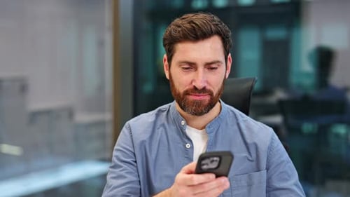 Happy Businessman Using Phone in Modern Office